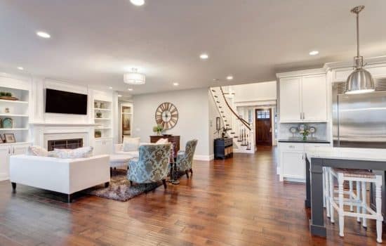 An open living space that bridges a family room area and kitchen space with a foyer in the background.