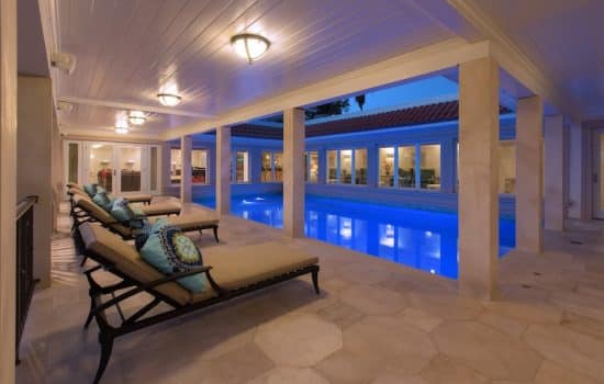 A tiled patio with a glowing pool, surrounded by marbled columns.